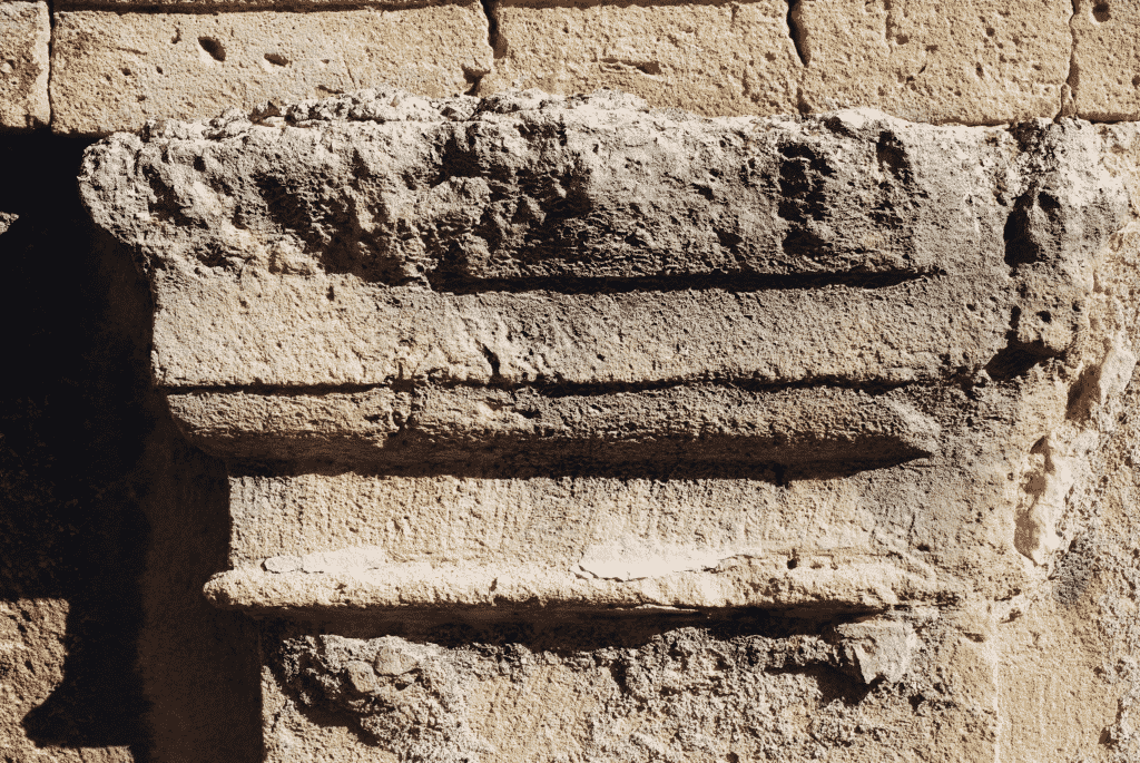 Dettaglio di uno dei capitelli tuscanici di lesena, conservato nel lato orientale della piazza (paramento ovest della Torre del Pretori), su cui sono visibili tracce di stucco.